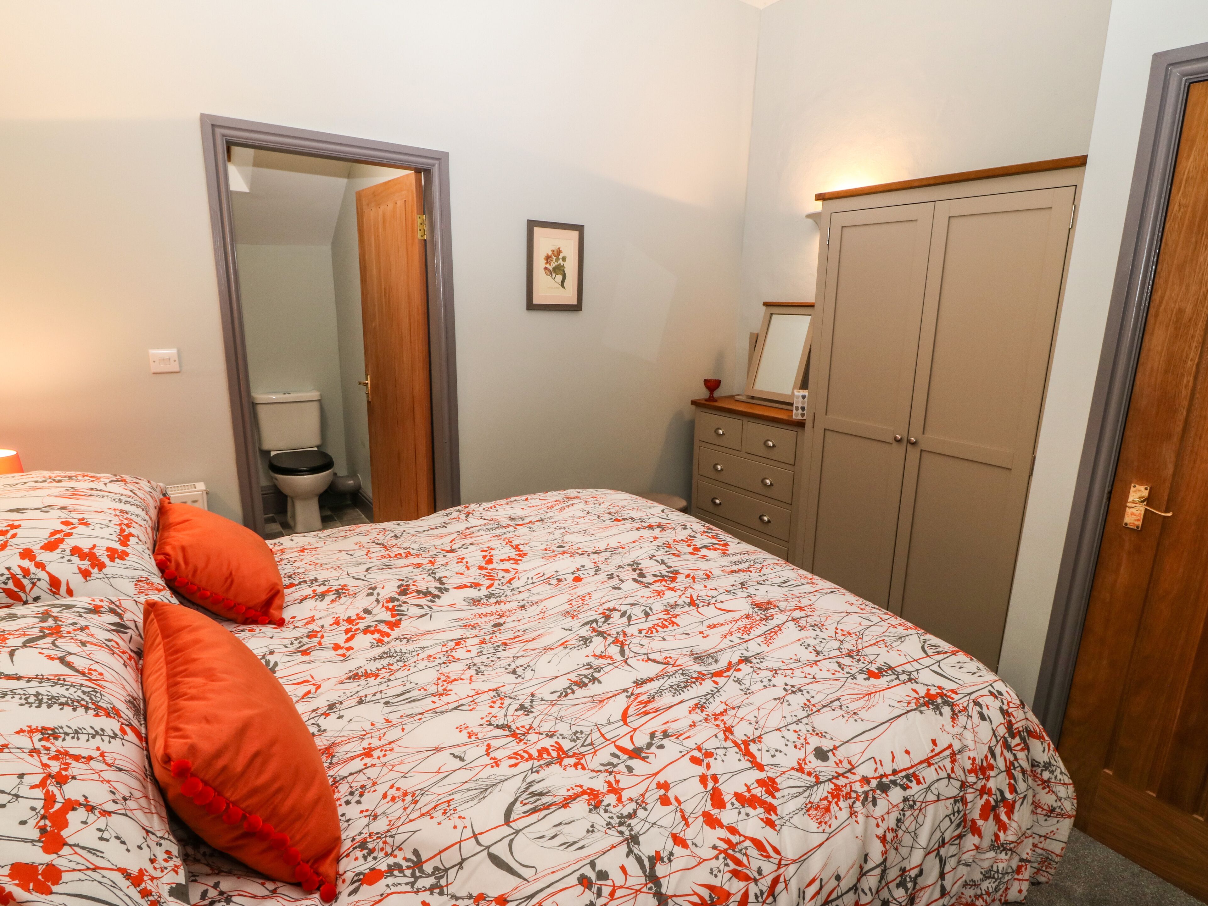 A bedroom with a bed, a dresser, a mirror, and a door.