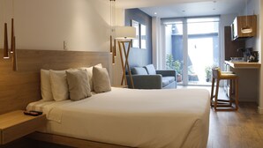 A modern hotel room with a large bed, a desk, and a view of the outdoors.