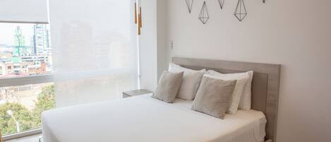 A modern bedroom with a large bed, a city view, and geometric wall art.