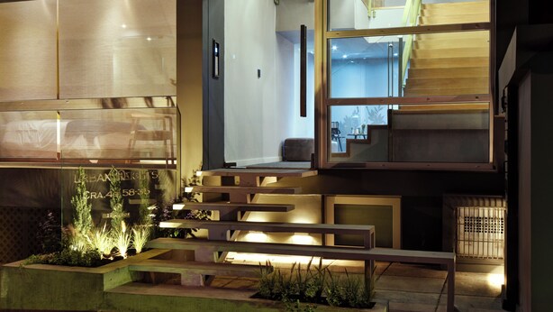 A modern building with a staircase, a bench, and a planter with plants.