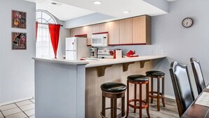 Una cocina moderna con una isla central, taburetes de bar y una mesa de comedor con sillas.