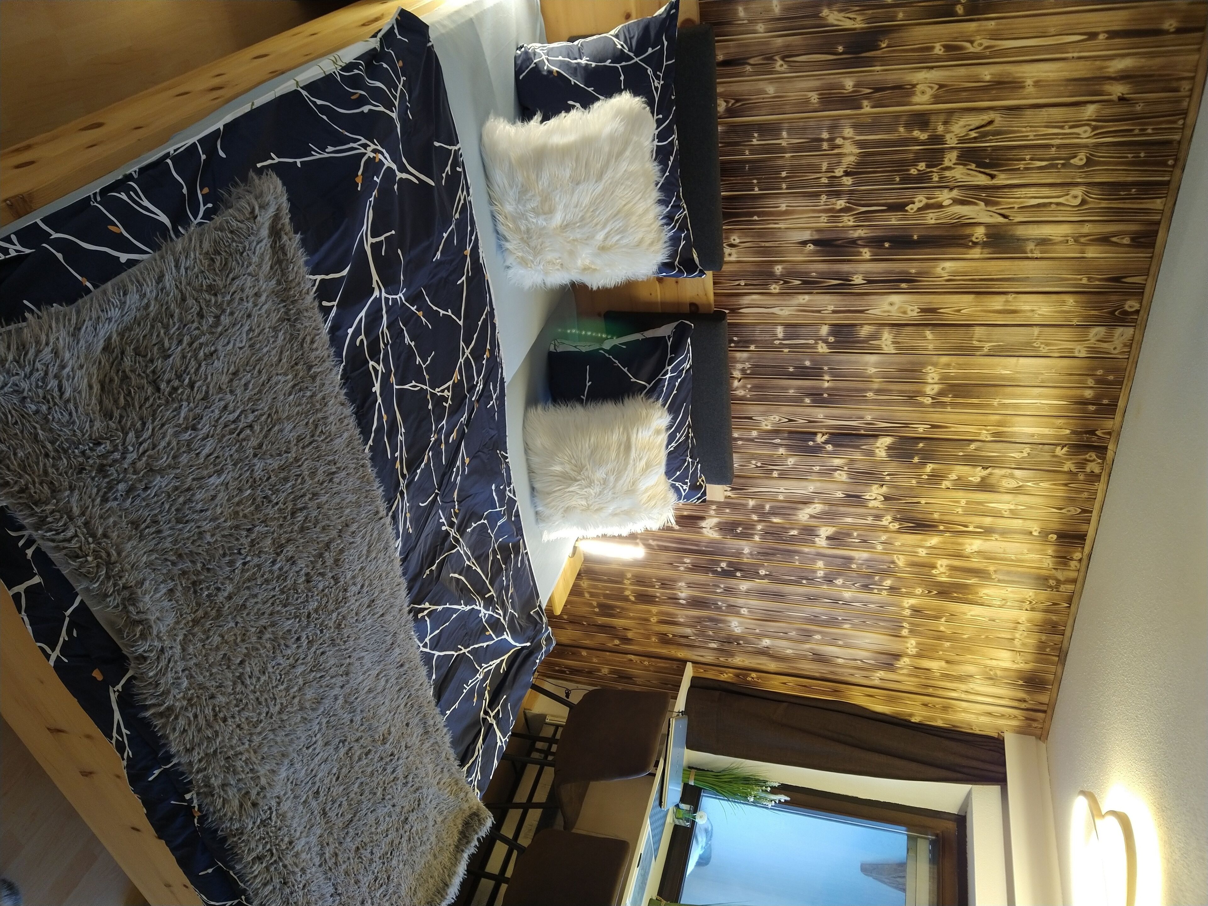 Una habitación con una cama, cabecera de madera, un tapete mullido y un panel de madera en la pared.