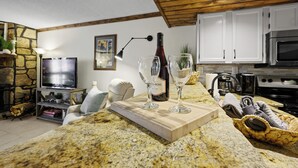 Une cuisine dotée de plans de travail en granit, d’armoires blanches, d’un four à micro-ondes et d’une cuisinière.