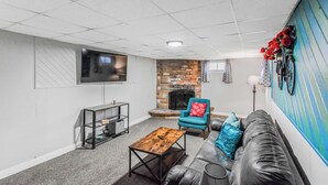 Un salon avec une cheminée en pierre, un téléviseur fixé au mur, un canapé et une table basse.