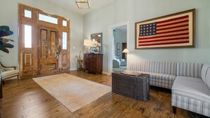 Ein Wohnzimmer mit Holzböden, einer großen amerikanischen Flagge, einem Sofa, einer Kommode und einer Tür.