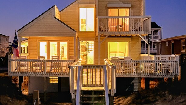Une maison à deux étages avec un balcon, un escalier et un drapeau.