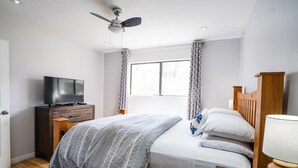 A bedroom with a bed, a TV on a dresser, a ceiling fan, and a window with curtains. - Pet friendly/walk to restaurant/bar and golf  (Flagstaff)