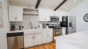 A modern kitchen with white cabinets, stainless steel appliances, and a wooden floor. - Pet friendly/walk to restaurant/bar and golf  (Flagstaff)