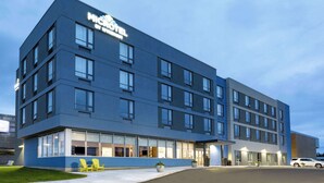 Un hotel moderno con tejado plano, numerosas ventanas y un área de entrada bien iluminada.