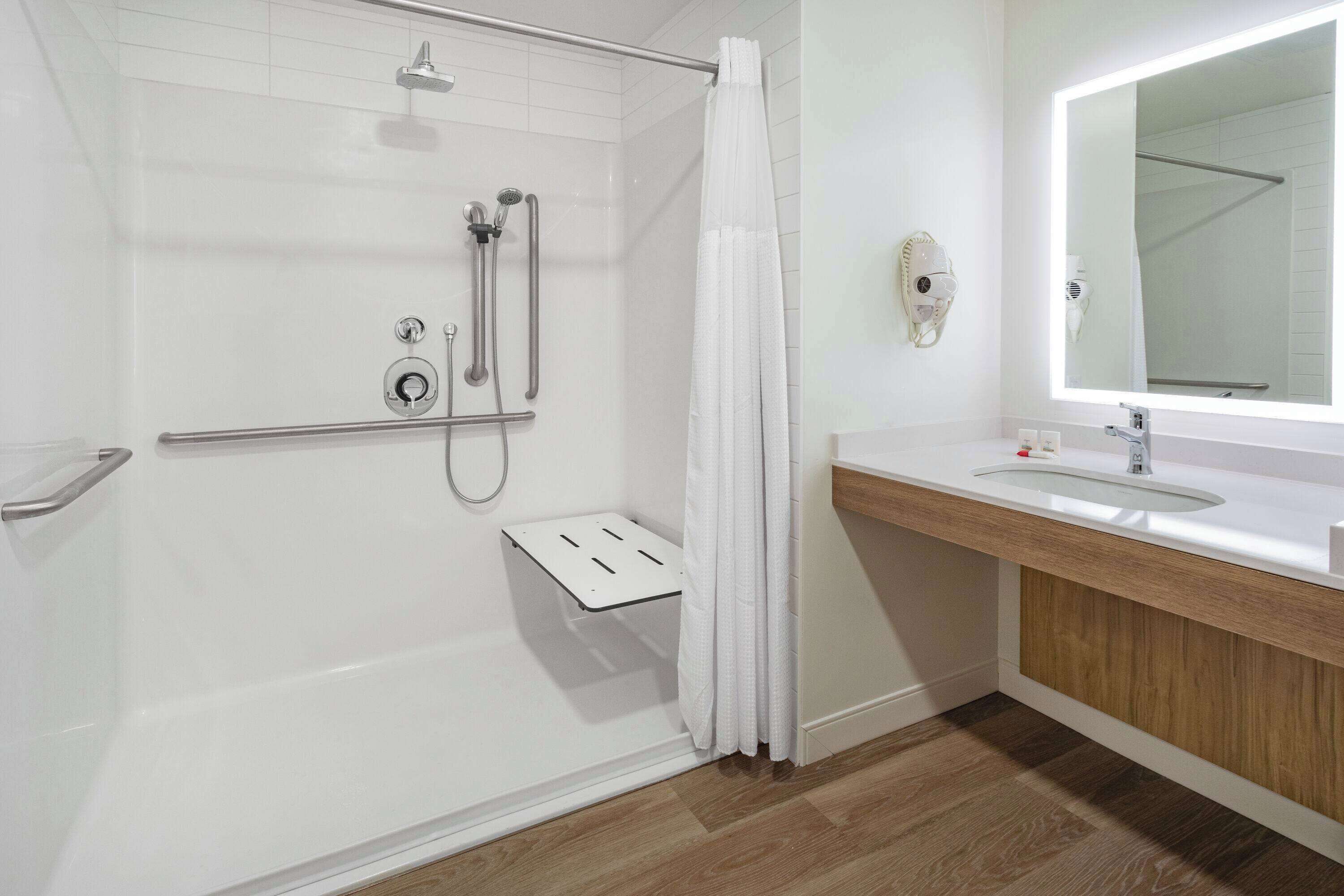 A modern bathroom with a walk-in shower, a vanity with a mirror, and a toilet.