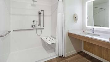 A modern bathroom with a walk-in shower, a vanity with a mirror, and a toilet.