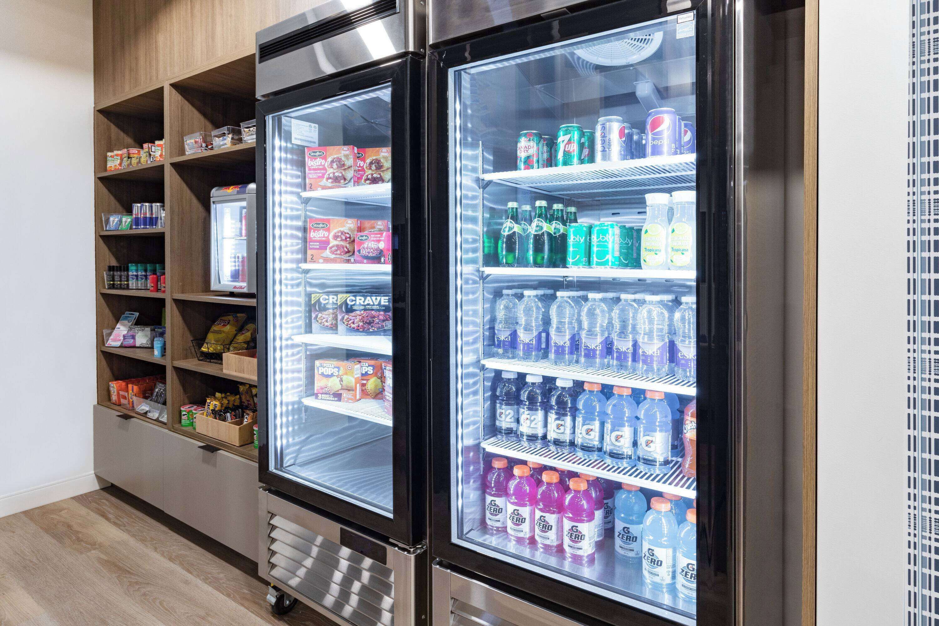Un distributeur automatique proposant une variété de collations et de boissons, notamment des sodas et de l’eau en bouteille.