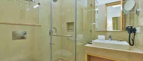 Un bagno moderno con cabina doccia in vetro, lavandino bianco e un grande specchio.