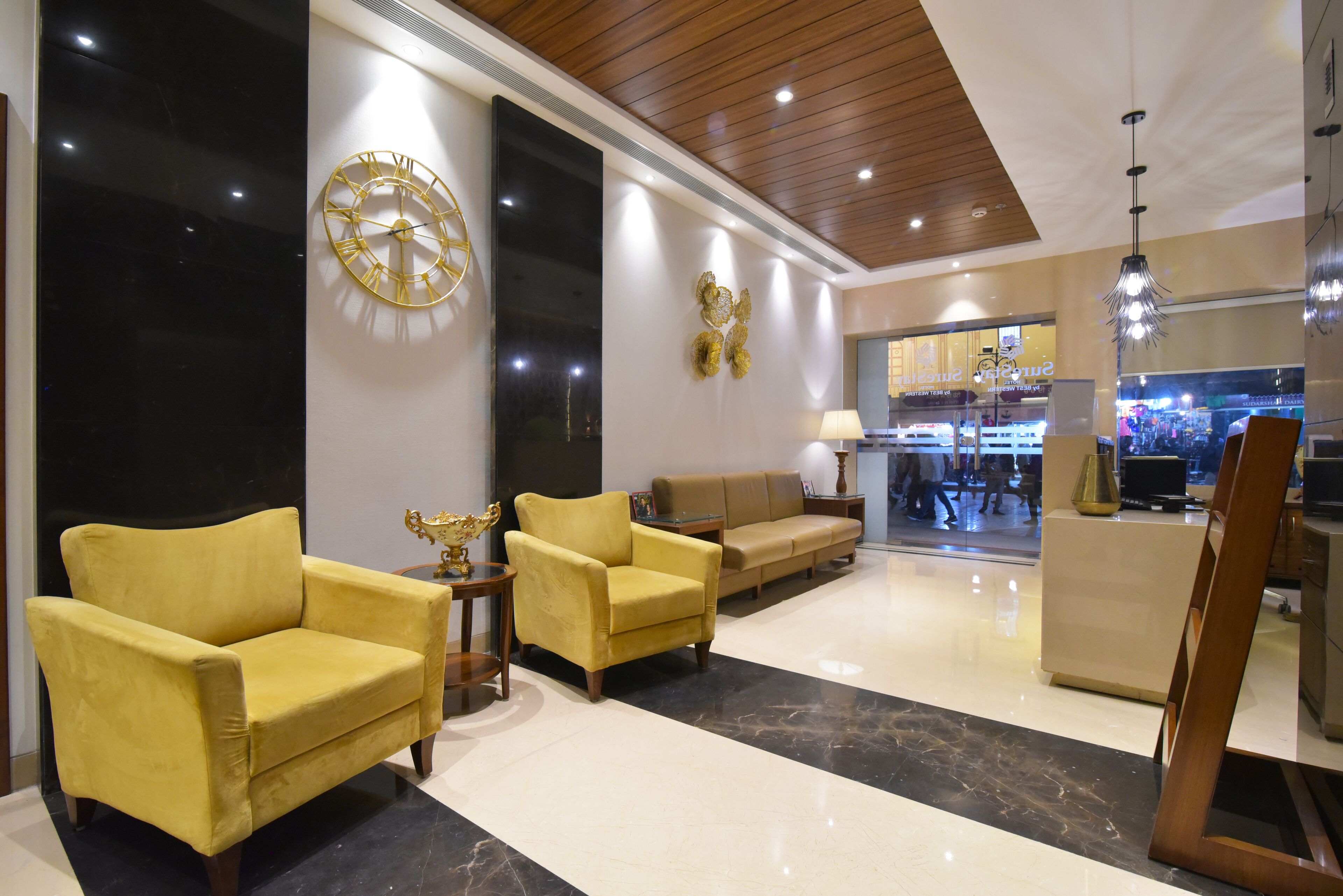 A lobby with a large clock, two sofas, a coffee table, and a reception desk.