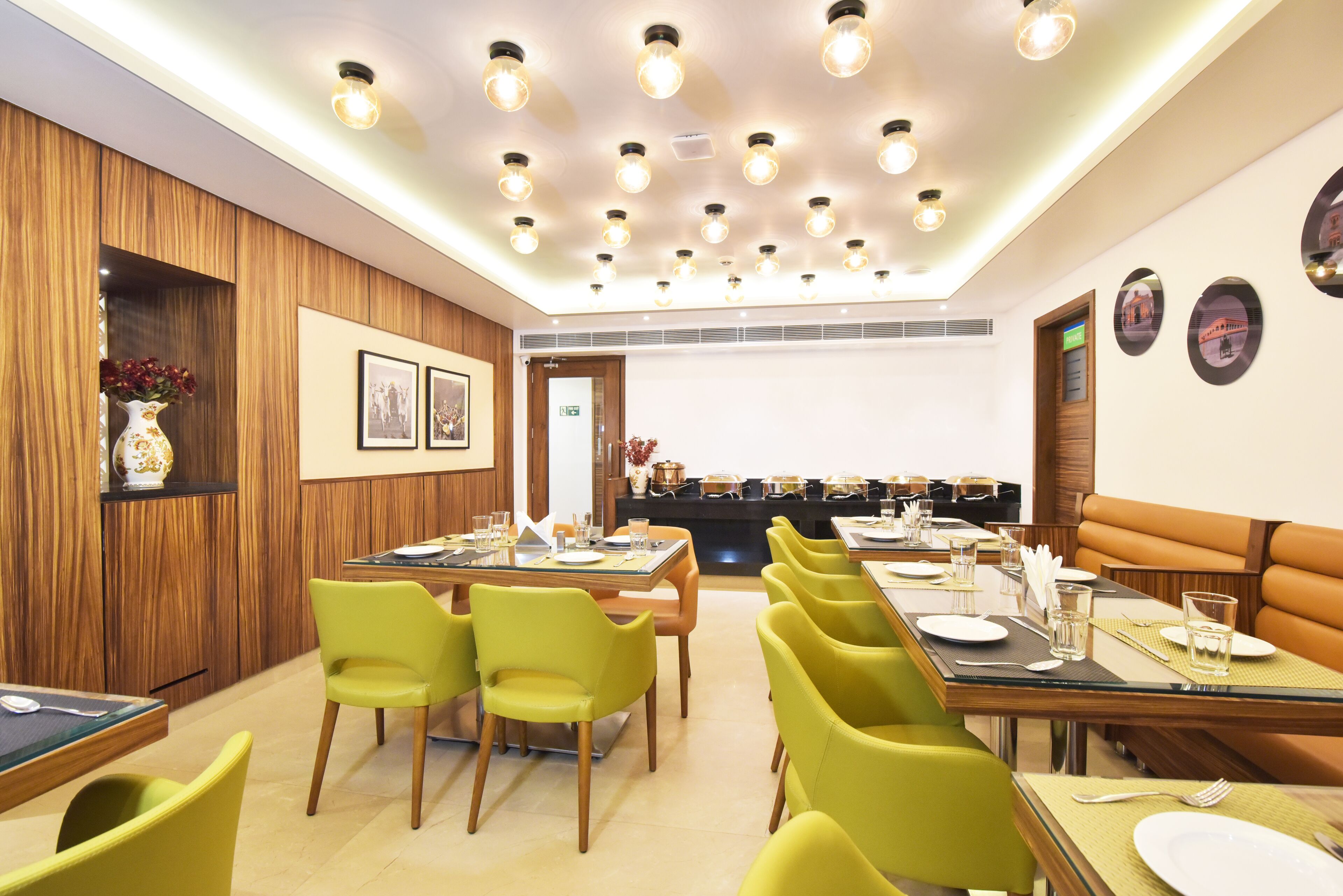Un comedor con varias mesas y sillas, paneles de madera en las paredes e iluminación empotrada en el techo.