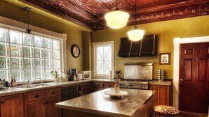 Une cuisine avec des meubles de rangement en bois, un grand îlot central doté de tabourets, une cuisinière et un four à micro-ondes.