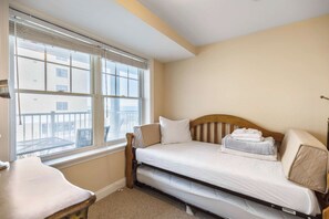 Un dormitorio con una cama individual, una mesita de noche, una silla y una ventana con persianas.