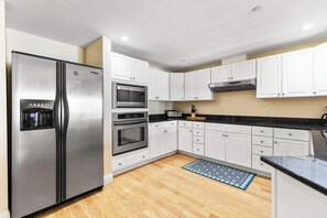 Una cocina moderna con electrodomésticos de acero inoxidable, armarios blancos y encimera negra.