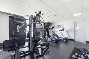 Ein Fitnessstudio mit verschiedenen Trainingsgeräten, darunter Laufband, Kraftgeräte und ein Ergometer.