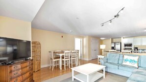 A living room with a TV, wooden dresser, white coffee table, and a blue sofa.