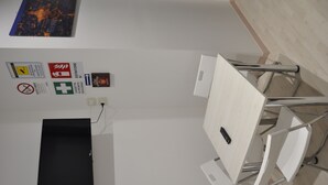 Ein Konferenzraum mit einem schwarzen Tisch, weißen Stühlen und einer Whiteboard-Tafel. An den Wänden befinden sich Schilder, die die Ausstattungsmerkmale und Annehmlichkeiten des Raumes kennzeichnen.