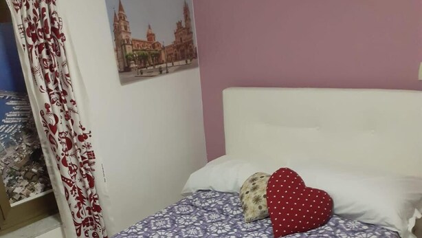 Ein ordentlich bezogenes Bett mit einem gemusterten Überwurf, Kissen und gefalteten Handtüchern.