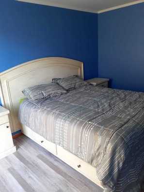 A bedroom with a bed, nightstands, and a dresser.