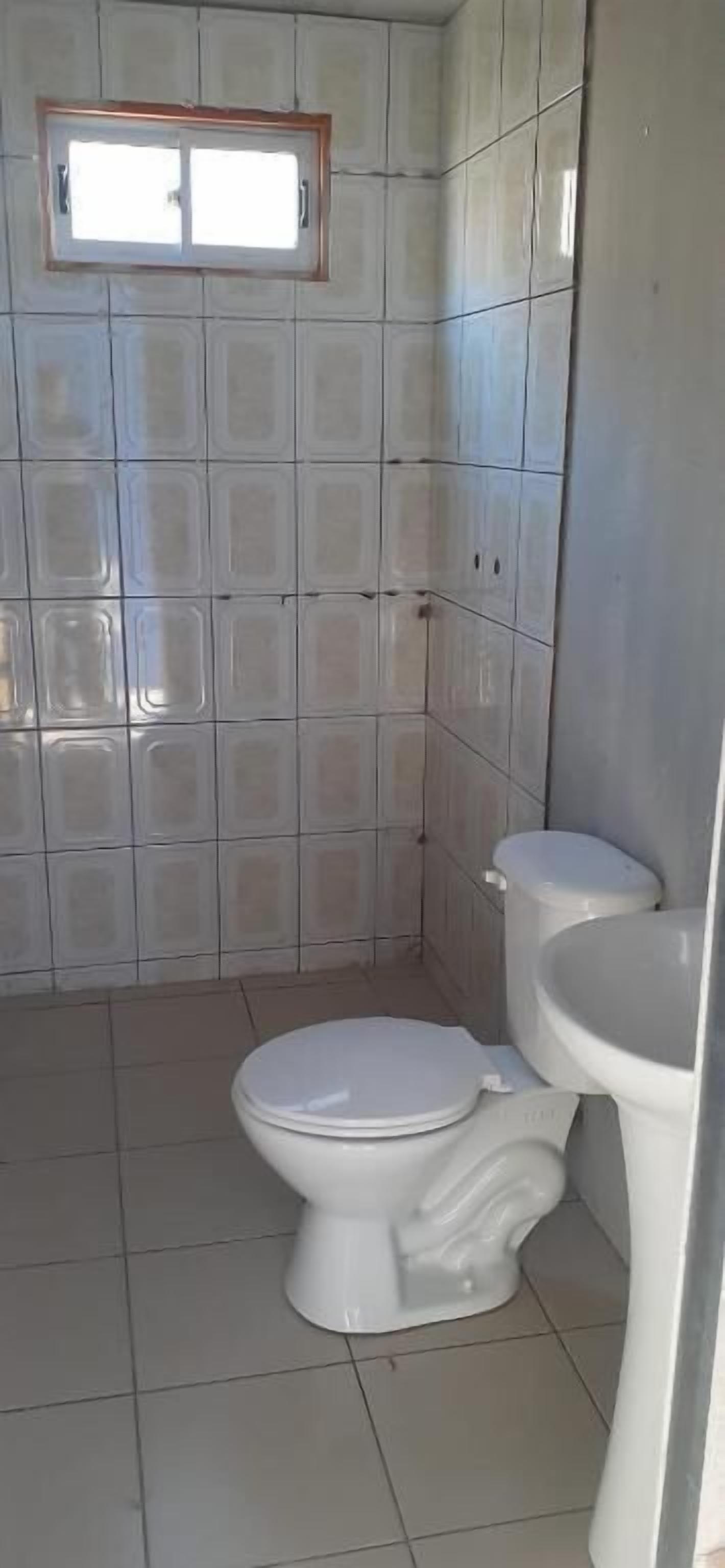 Un baño pequeño con inodoro, lavamanos y una ventana sobre el inodoro.