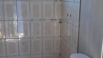 Un baño pequeño con inodoro, lavamanos y una ventana sobre el inodoro.