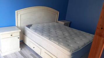A bedroom with a single bed, a nightstand, and a dresser.