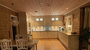 Une cuisine moderne avec des meubles en bois, un îlot central et un coin repas avec des chaises blanches.