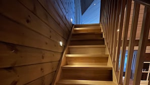 Un escalier en bois avec une rampe, qui monte.