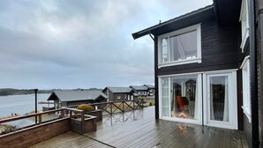 Une terrasse en bois offrant une vue sur un lac et des maisons en arrière-plan.