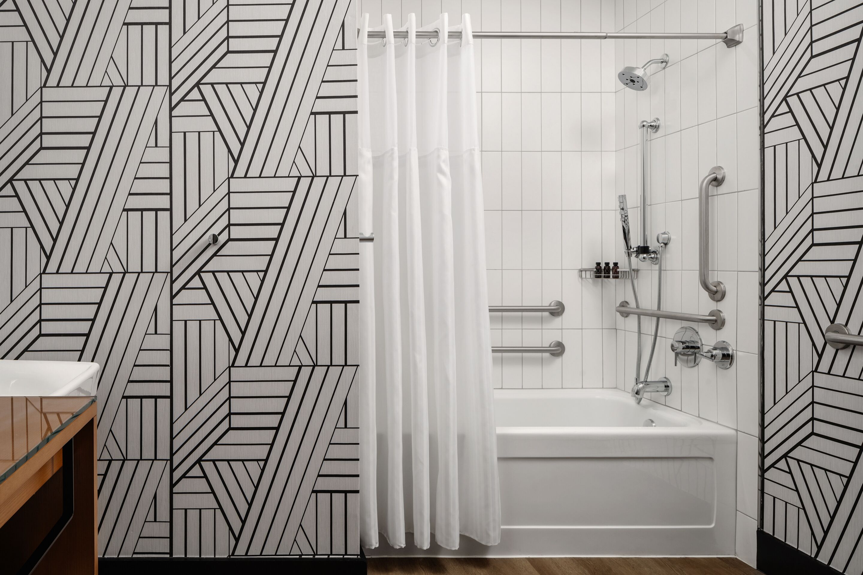 A modern bathroom with a geometric patterned wall, a white bathtub, and a shower with a curtain.