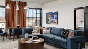A modern living room with a blue sofa, a round coffee table, and a cityscape view through large windows.