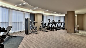 A modern gym with cardio machines, weightlifting equipment, and large windows with sheer curtains. - Wyndham Garden Hangzhou Yuhang (Hangzhou)