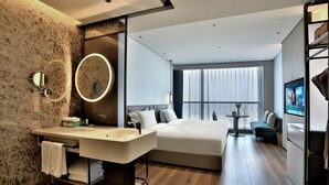 A modern hotel room with a large bed, a vanity with a mirror, a small table, and a sofa. - Wyndham Garden Hangzhou Yuhang (Hangzhou)