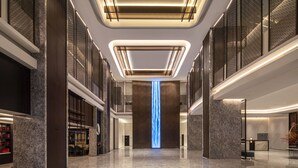 A modern hotel lobby with a central light feature, marble floors, and a reception desk. - Wyndham Garden Hangzhou Yuhang (Hangzhou)