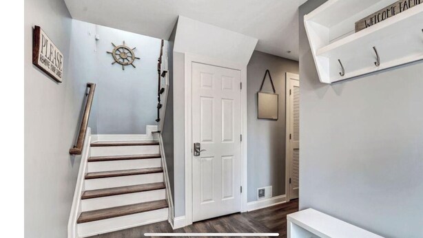 A staircase with a wooden handrail leading to a white door. - Beautiful New Spacious Townhome w/ Pool, Steps to Beach/Boardwalk, 3 Levels (Seaside Heights)