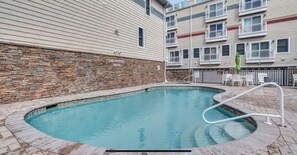 Une piscine avec un mur en pierre et un panneau indiquant qu’il est interdit d’utiliser des jouets gonflables.