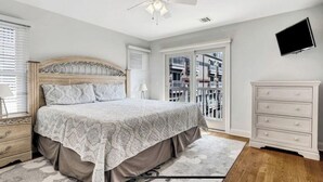 A bedroom with a bed, dresser, TV, and balcony. - Beautiful New Spacious Townhome w/ Pool, Steps to Beach/Boardwalk, 3 Levels (Seaside Heights)
