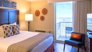 A hotel room with a large bed, a desk, a chair, and a balcony with a view. - Two Bedroom Ocean Front Condo, Ormond Beach 2555514 (Ormond Beach)