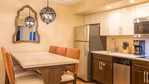 A kitchen with a wooden dining table, chairs, a refrigerator, a dishwasher, and a microwave. - Two Bedroom Ocean Front Condo, Ormond Beach 2555514 (Ormond Beach)