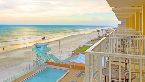 A balcony with a view of a beach and a lifeguard tower. - Two Bedroom Ocean Front Condo, Ormond Beach 2555514 (Ormond Beach)