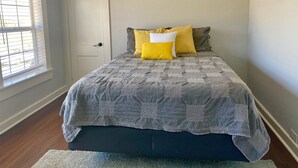 Un dormitorio con una cama, una ventana con persianas y una puerta.