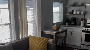 Una sala de estar moderna con un sofá gris, una mesa de centro de madera y una cocina al fondo.