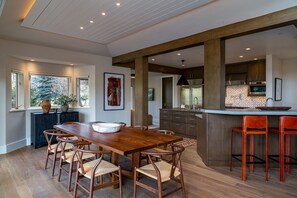 A spacious kitchen with a large island, wooden dining table, and chairs. - Luxurious Sun Valley Mountain Retreat on Golf Course (Sun Valley)