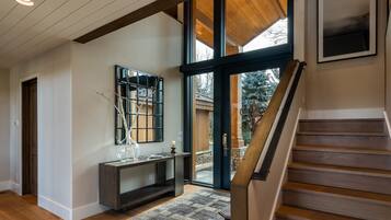 Un intérieur moderne avec un escalier en bois, une grande fenêtre et une console agrémentée d’objets décoratifs.