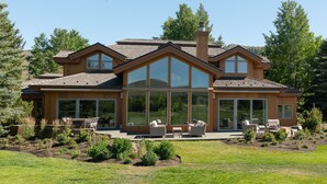 A modern house with large windows, a covered patio, and a landscaped garden. - Luxurious Sun Valley Mountain Retreat on Golf Course (Sun Valley)