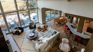 A spacious living area with a large sofa, a dining table, and a kitchen area. - Luxurious Sun Valley Mountain Retreat on Golf Course (Sun Valley)
